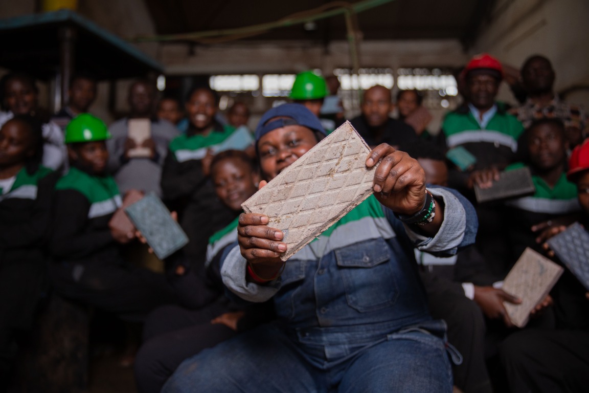 The Gjenge Makers team holding recycled plastic building bricks
