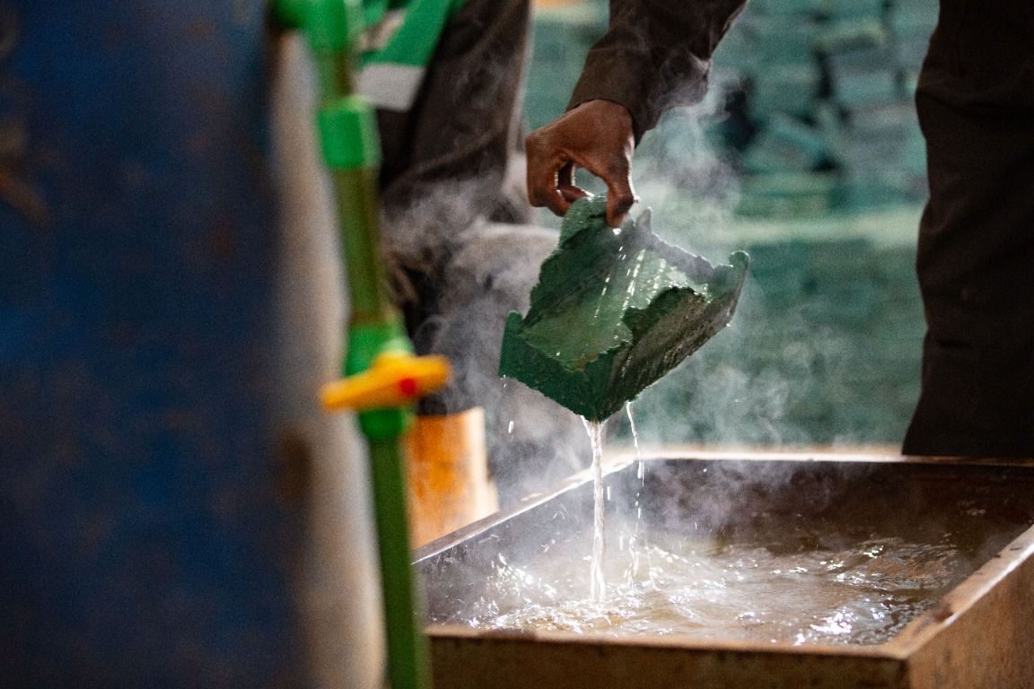 Hot green recycled plastic being cooled in a water trough